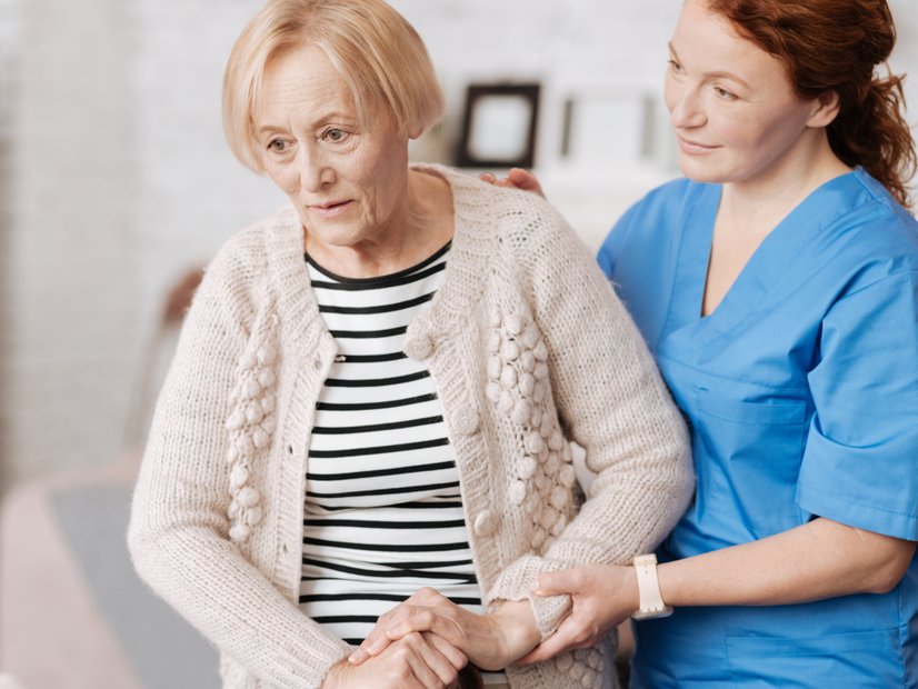 Sturzprophylaxe in der Pflege: Pflegerin assistiert Seniorin