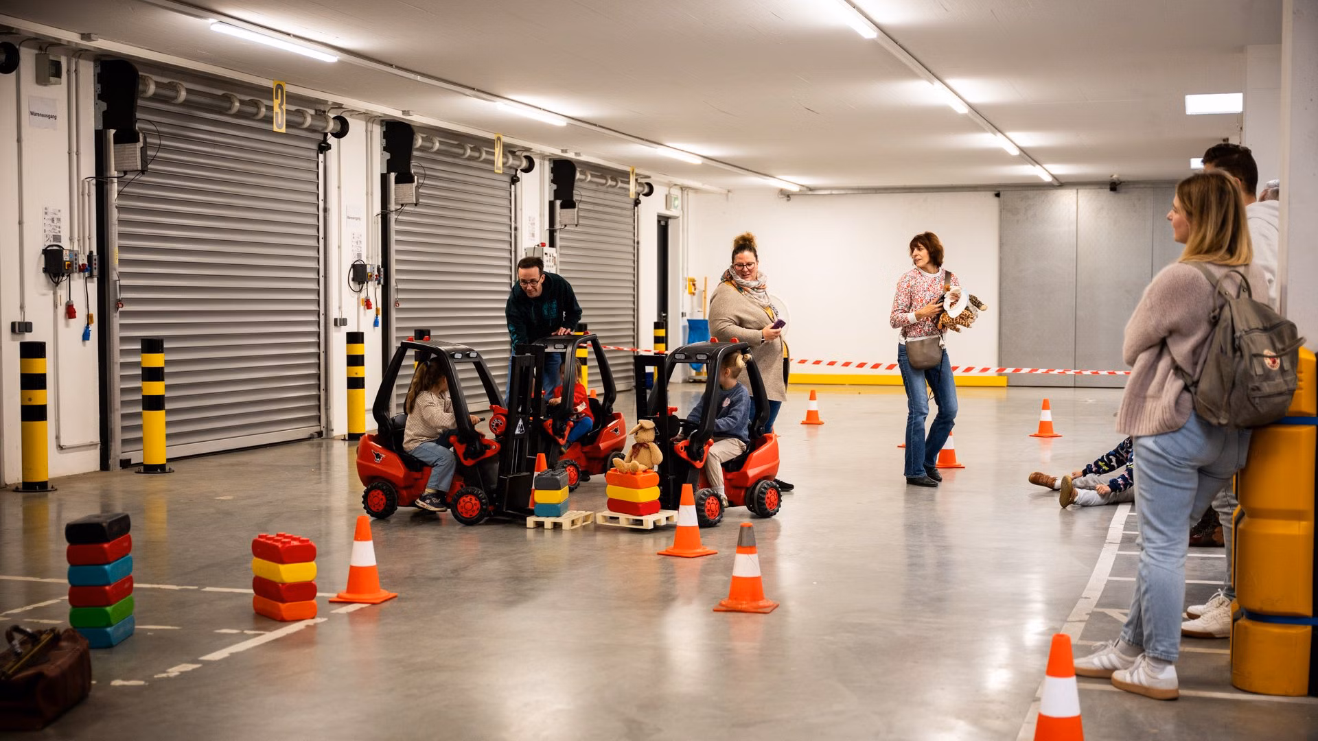 Einblicke ins Unternehmen Kinder fahren spielerisch durch einen Parcours in einer großen Halle