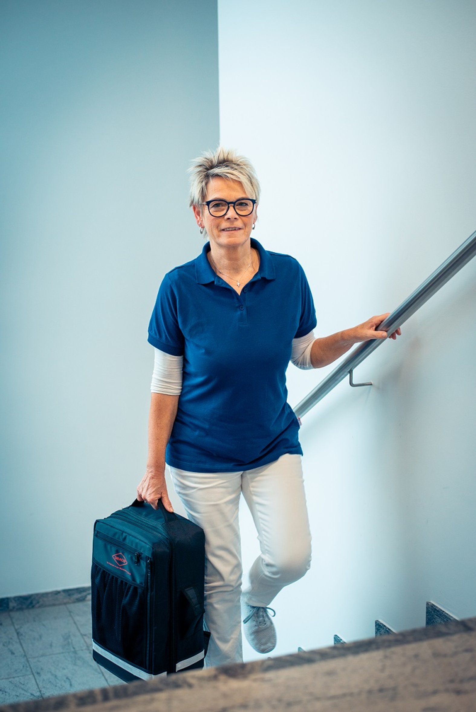 Der Hausbesuchsrucksack im Einsatz wird die Treppe hochgetragen