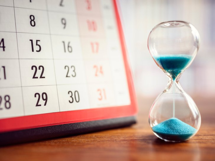 Sanduhr mit Kalender im Hintergrund