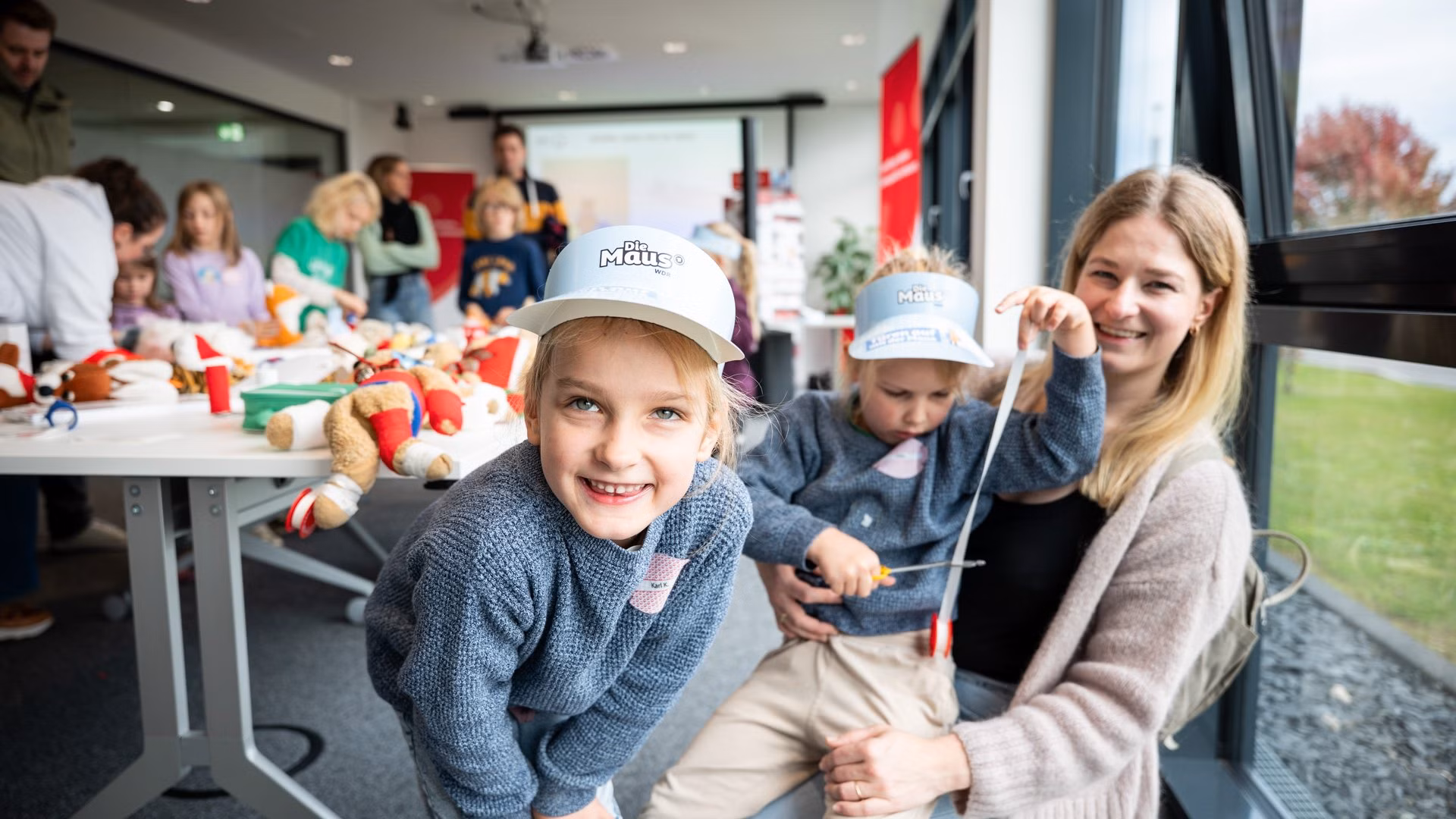Maus Türöffner Tag Familien Kind lächelt in die Kamera während es mit Familie an einer Mitmachaktion teilnimmt