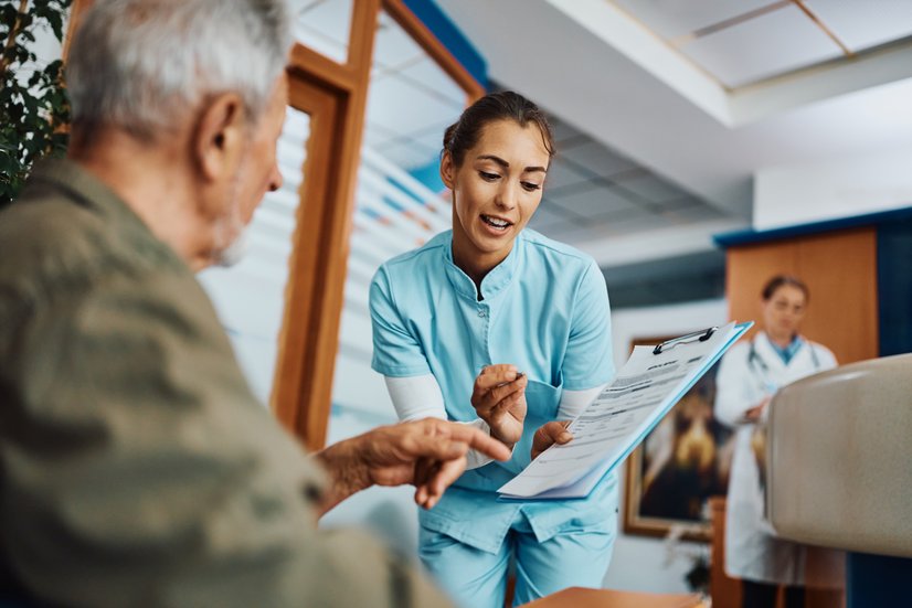 Wartezimmer, MFA erklärt Patient ein Formular