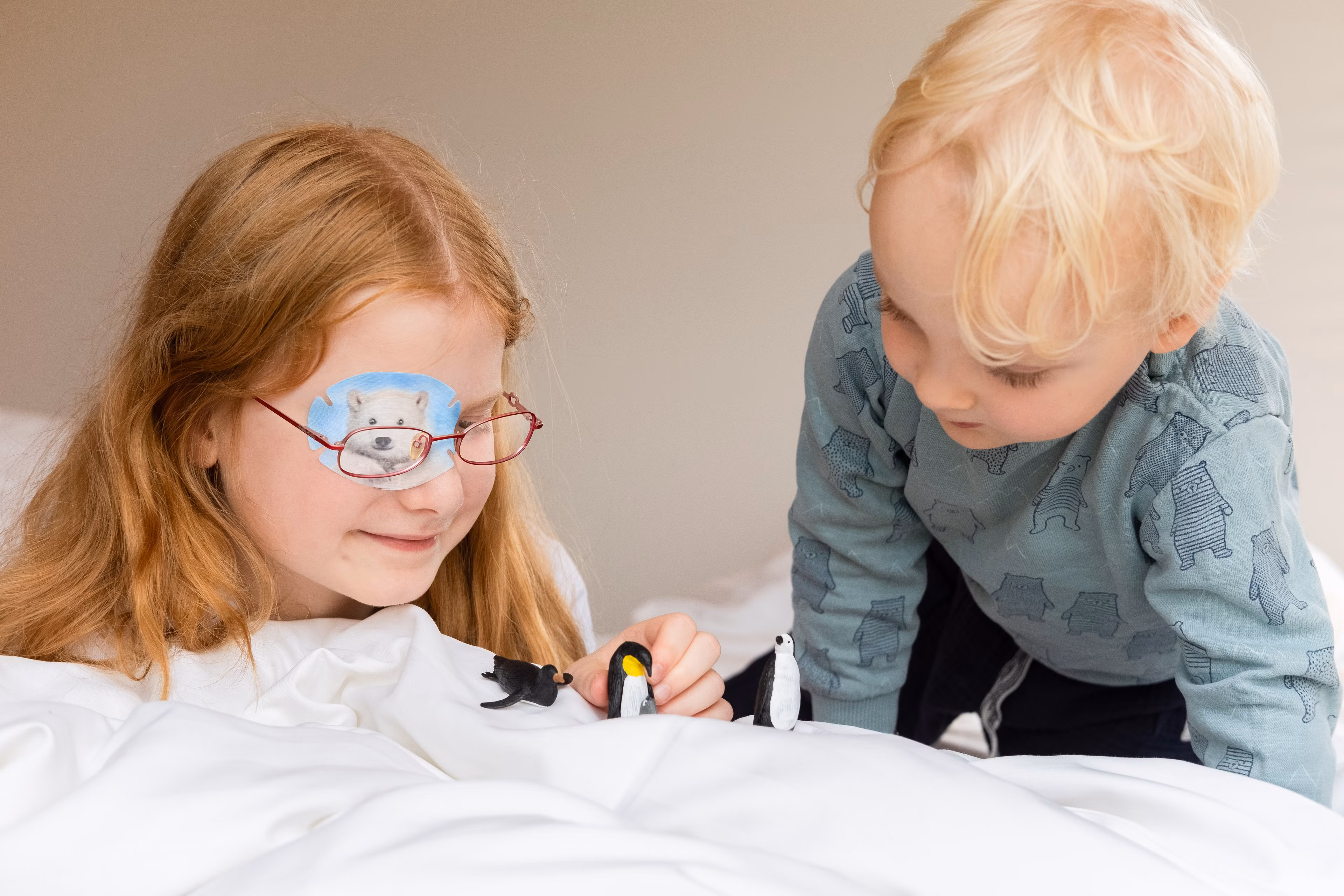 Kinder mit Augenpflaster lesen im Bett