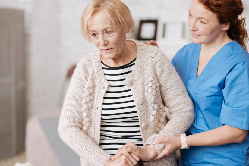Sturzprophylaxe in der Pflege: Pflegerin assistiert Seniorin